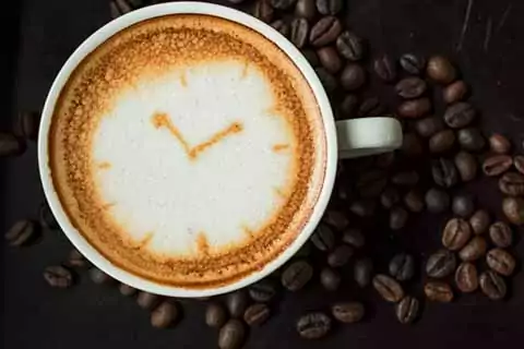 taza de cafe con espuma dibujo reloj