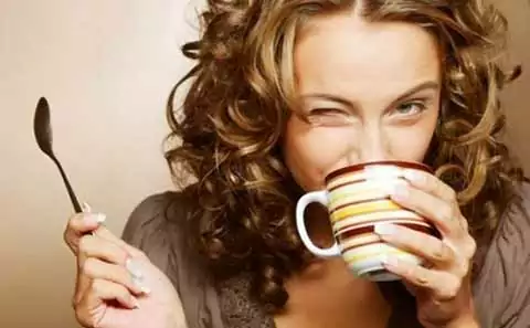 chica guiña un ojo mientras toma una taza de cafe