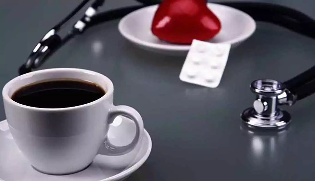 taza de cafe fonendoscopio pastillas sobre mesa gris