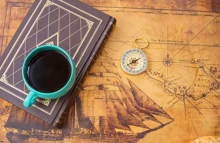 historia del cafe expreso taza cafe libro brujula sobre mapa